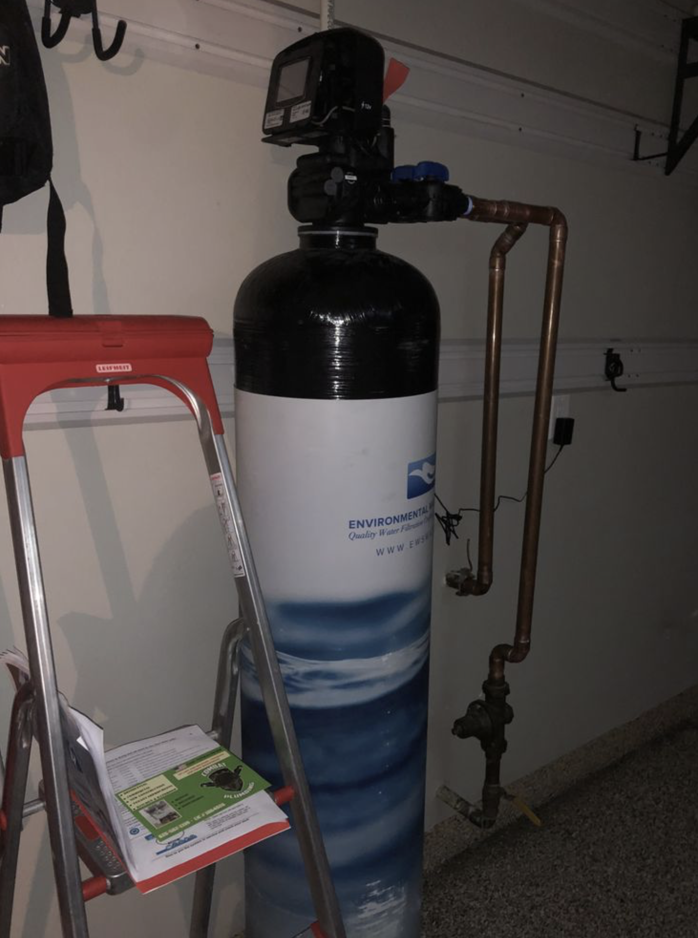 Whole-house water softener system installed in garage.