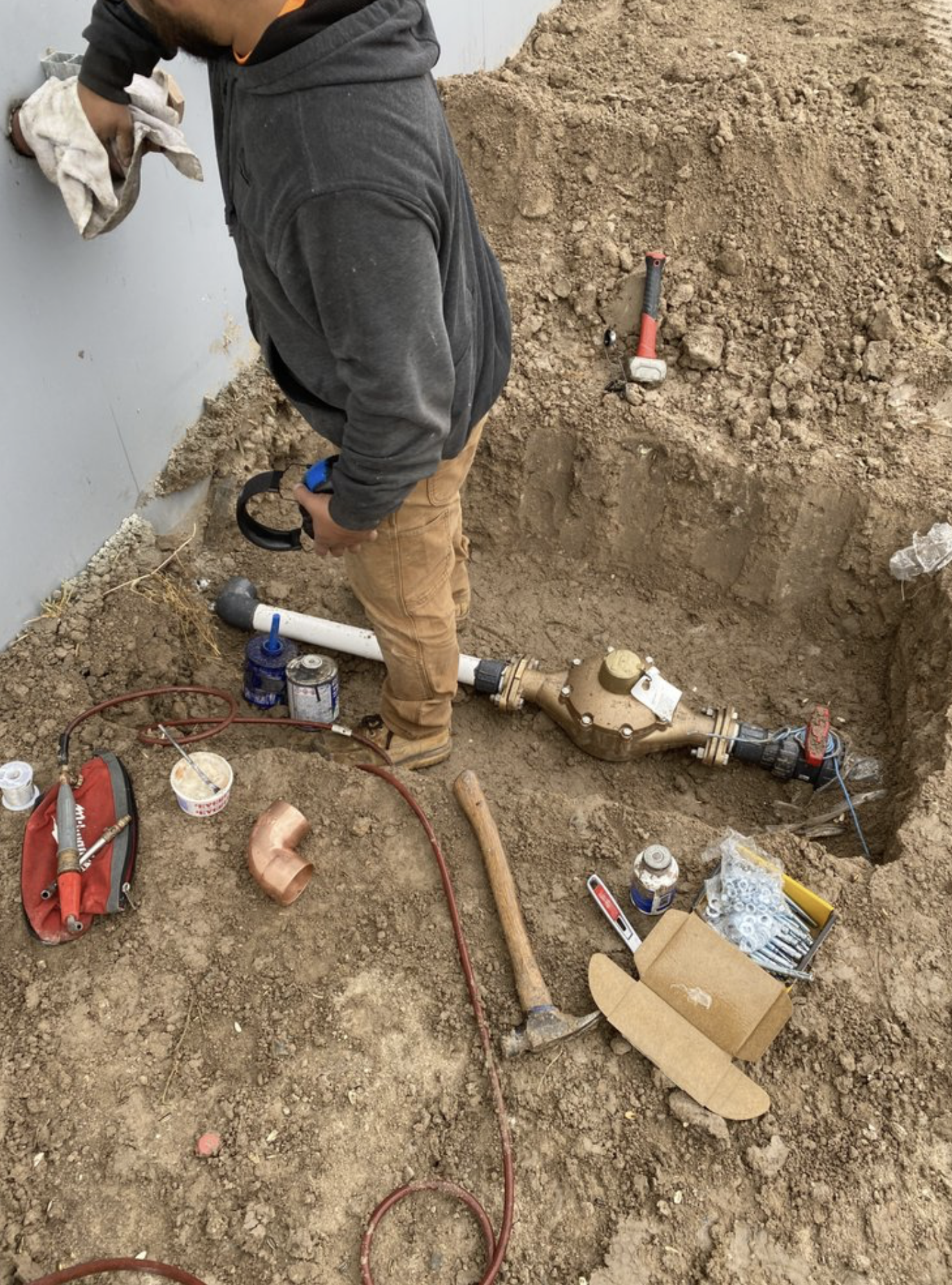 Plumber installing underground water service line.