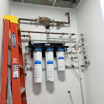 Whole-home water filtration system with multiple filters and copper piping.