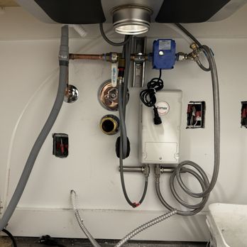 Under-sink plumbing with garbage disposal and shutoff valves.