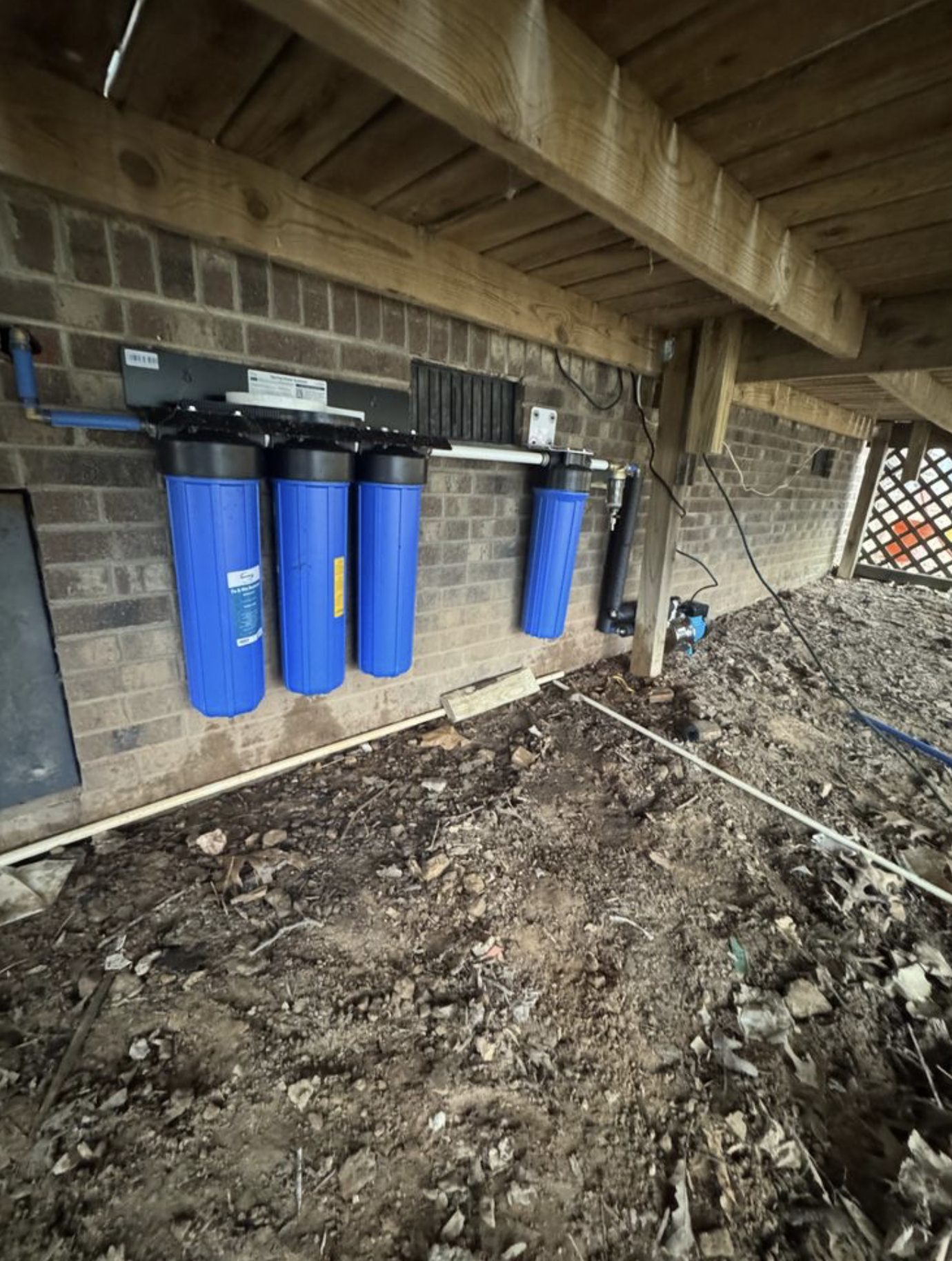 Under-home whole-house filtration system mounted to foundation.